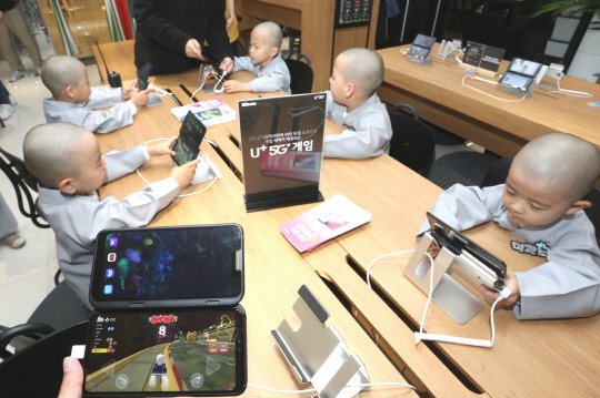 LG유플러스가 부처님 오신날을 맞아 조계사 동자승 10명을 '일상로5G길'로 초청, U+5G 서비스 체험행사를 가졌다. LG유플러스 '일상로5G길'을 방문한 조계사 동자승이 U+5G 게임 서비스를 체험하고 있다. LG유플러스 제공
